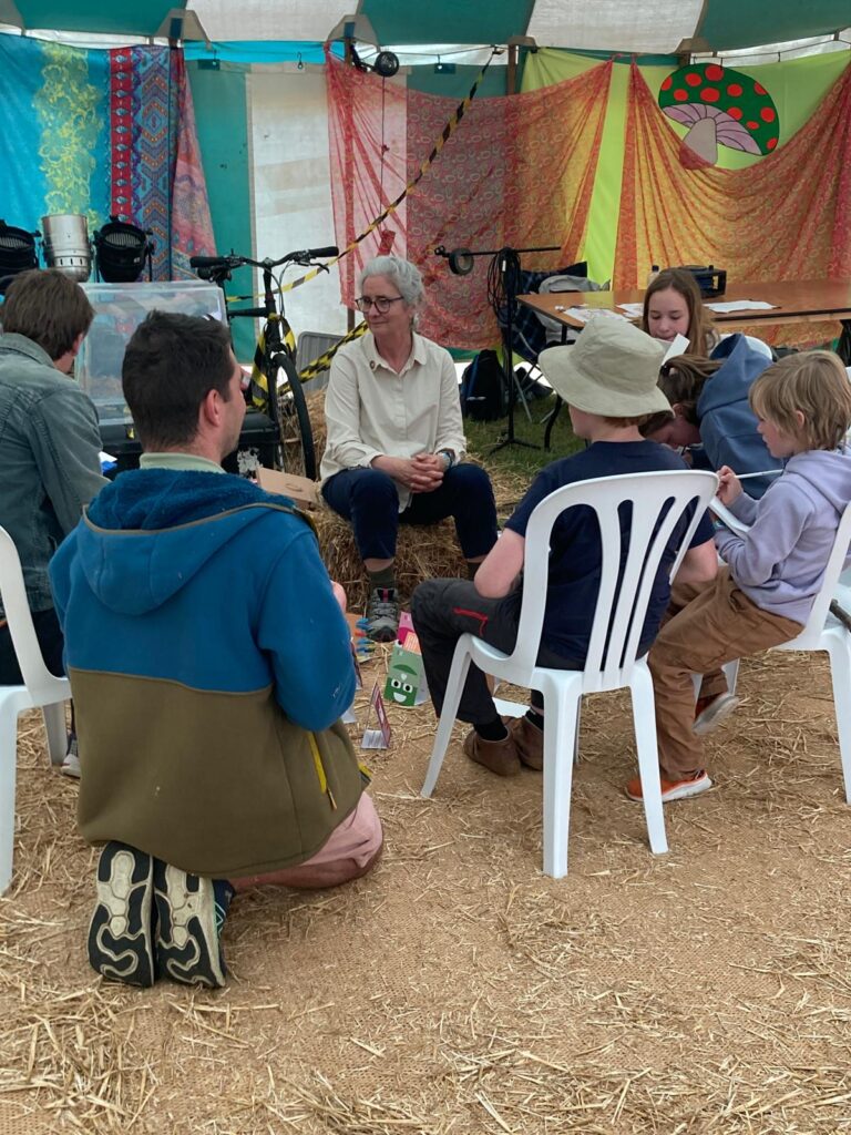 Wood Festival 26; People sitting around a game in a brightly coloured tent